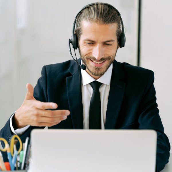 Confident businessman in suit with headset conducting an online meeting from office.